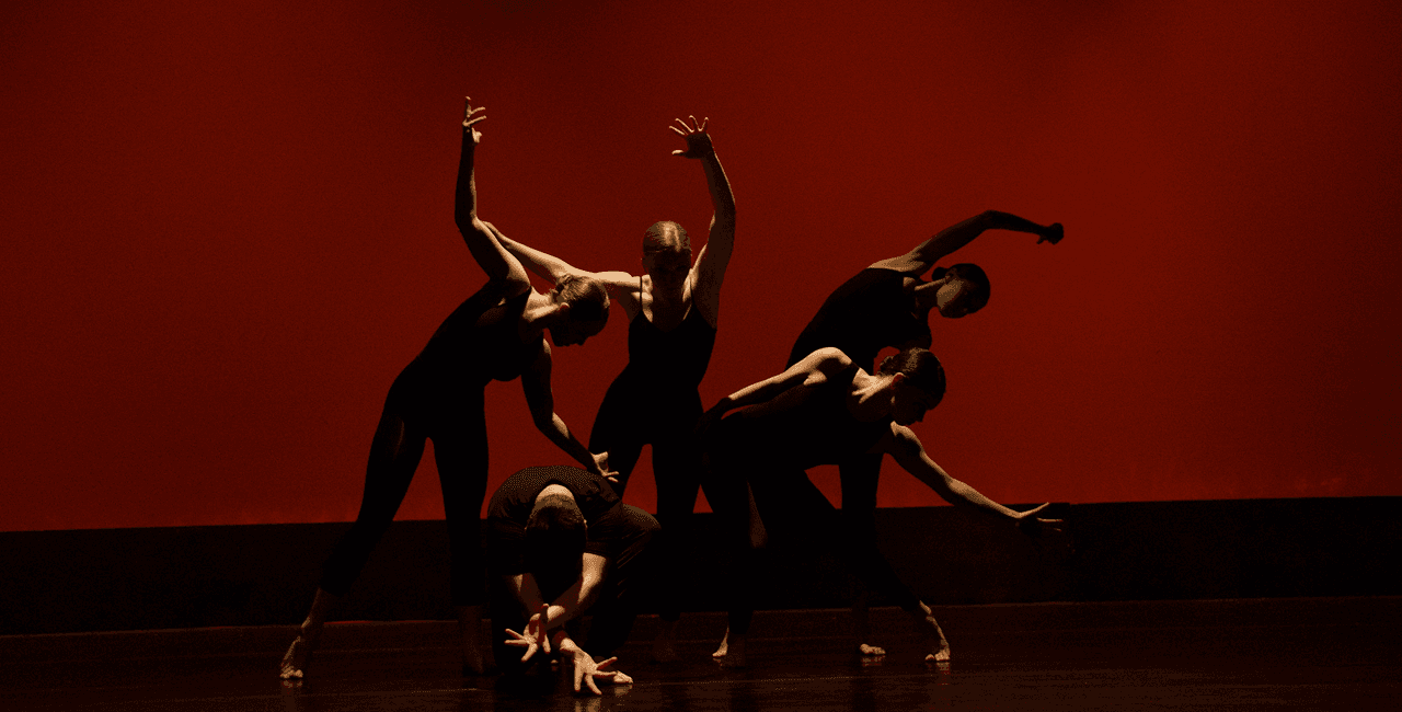 Photo of a group of modern dancers posing on a stage.