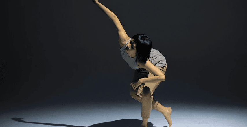 Photo of a female dancer in a modern dance pose with a spotlight on her.